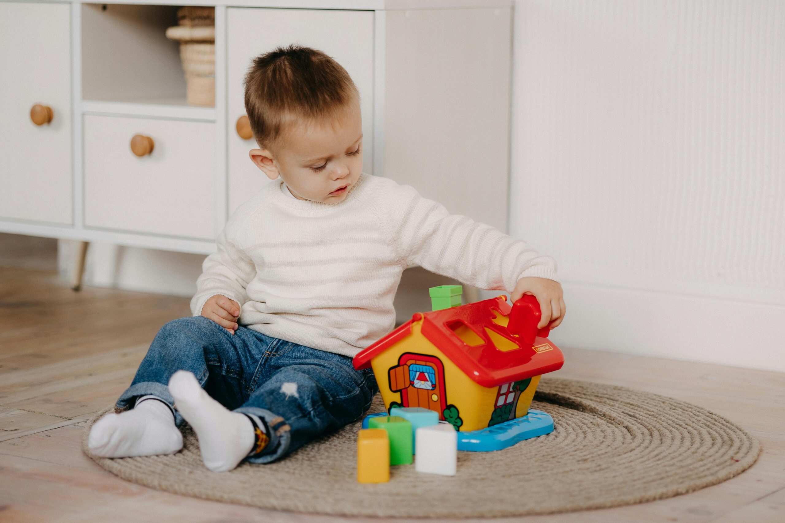 Kleiner Junge beschäftigt sich in gemütlicher häuslicher Umgebung mit buntem Lernspielzeug.
