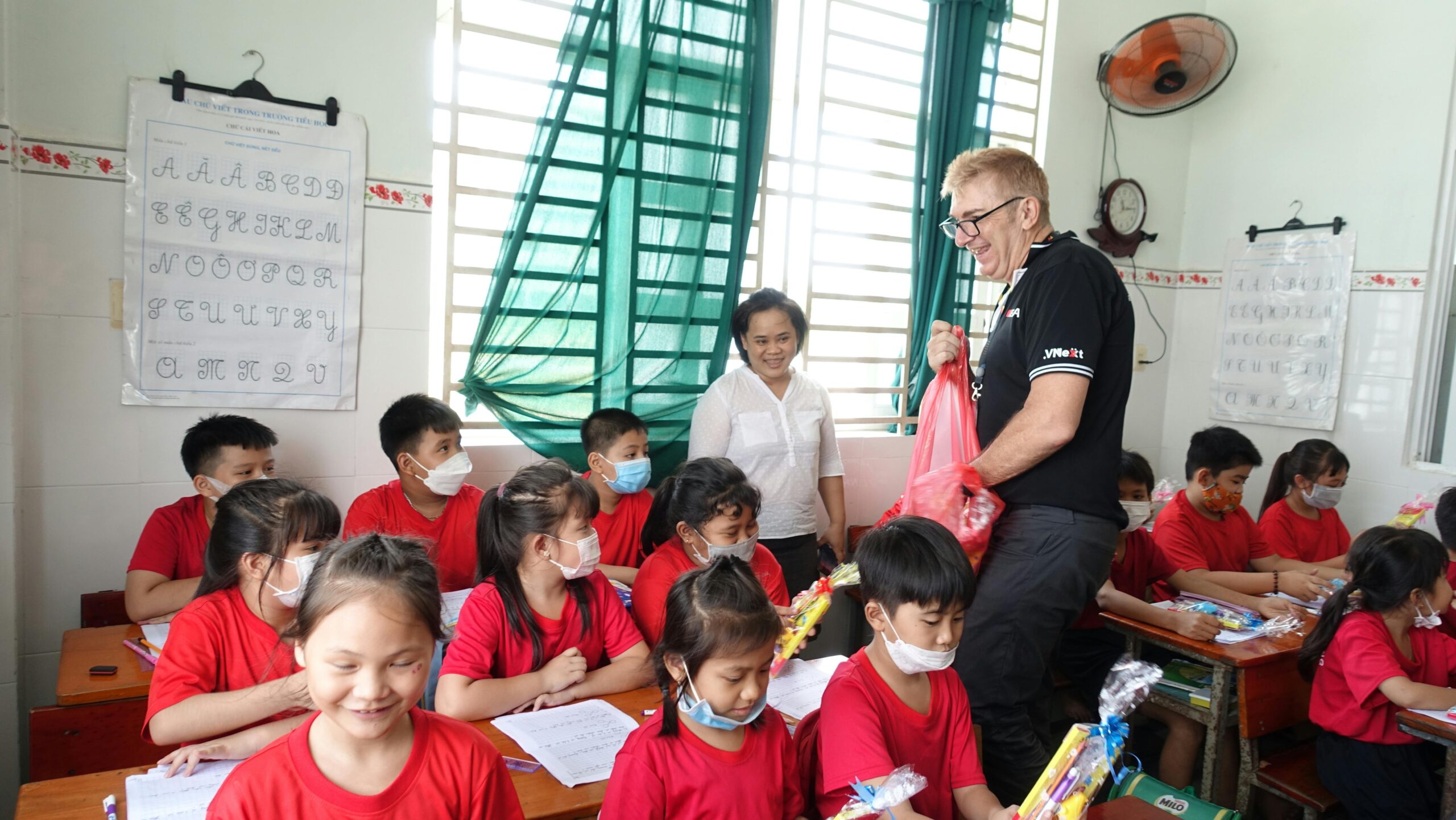 Ein Lehrer verteilt in einem vietnamesischen Klassenzimmer Geschenke an die Schüler.